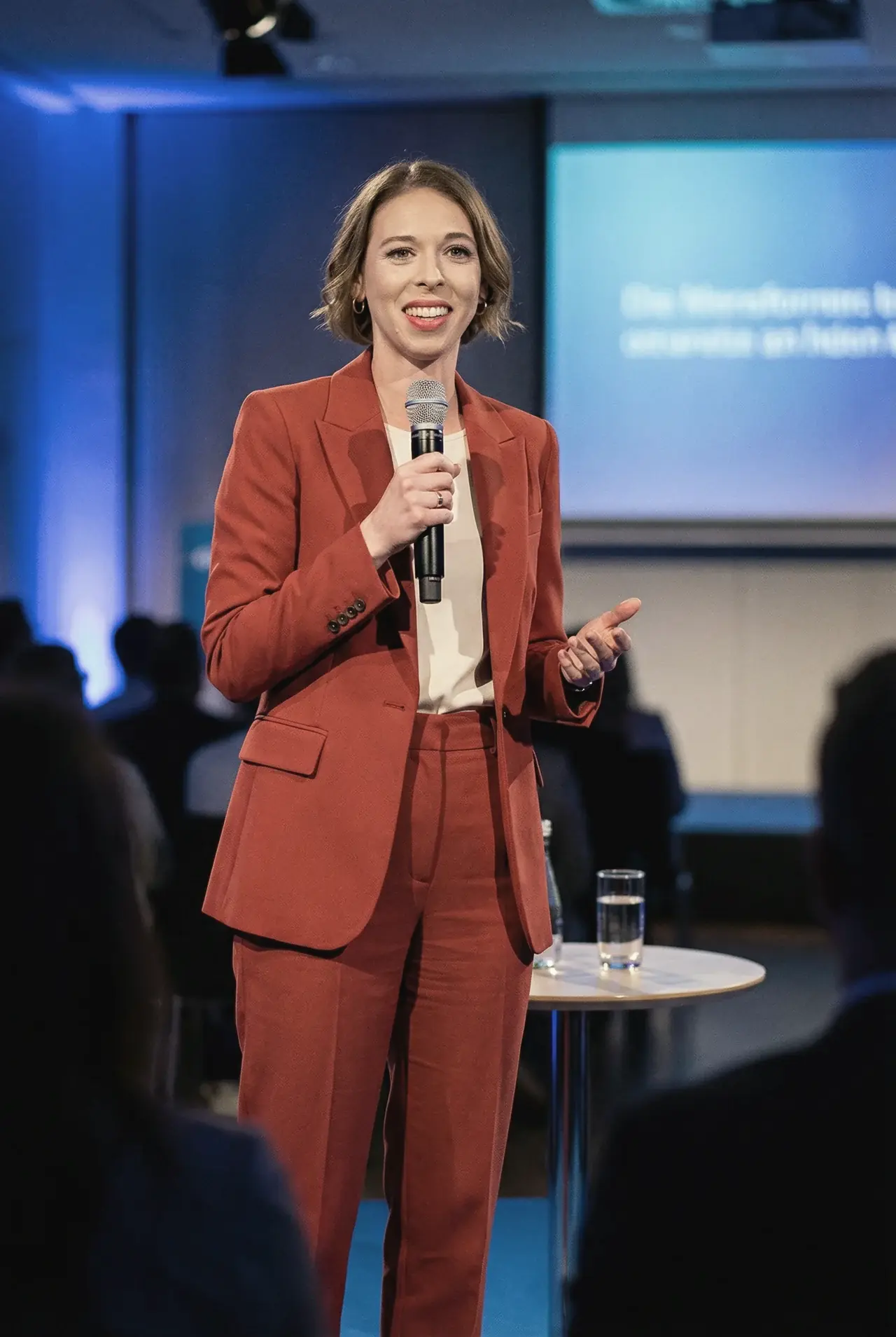 Dorothee Ebert spricht in einem roten Anzug mit einem Mikrofon vor Publikum.