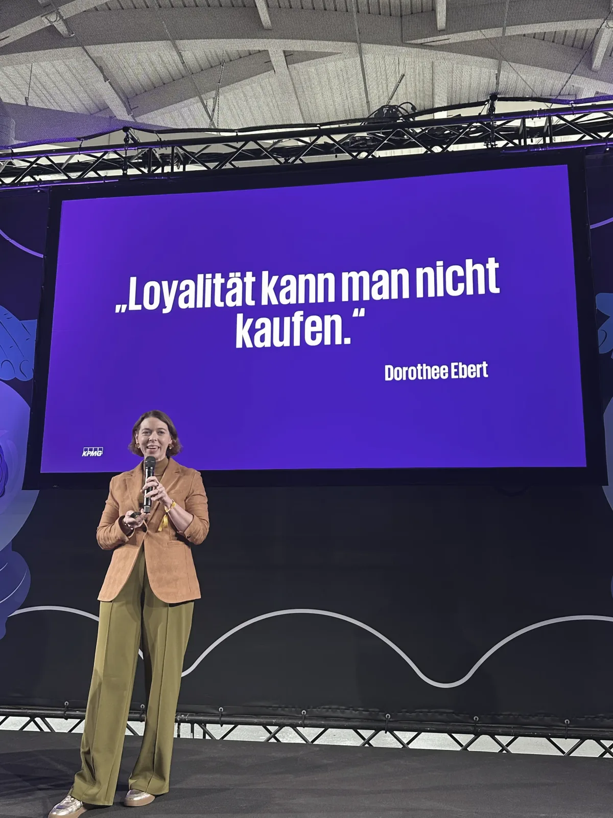 Dorothee Ebert spricht vor einer großen Bühne über Loyalität und Verbindung.